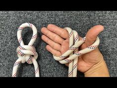 a hand holding two white and red ropes