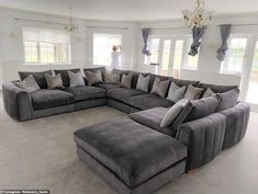 a large sectional couch in the middle of a living room with lots of pillows on it