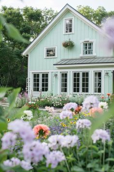 a blue house surrounded by flowers and trees