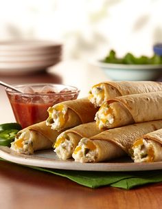 several burritos on a plate with salsa in the background