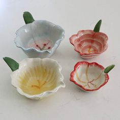 four small bowls with flowers in them sitting on a white counter top next to each other