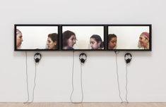 four framed pictures hanging on the wall with headphones attached to them, and three women's heads