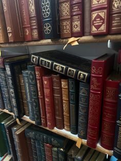 several rows of books are on the shelves in a library with gold trimmings