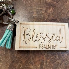 a wooden keychain with the words, blessing and tassels on it