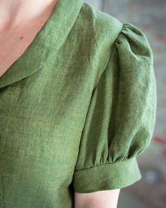 a woman wearing a green dress with puffy sleeves