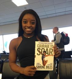 a woman holding up a book in an airport