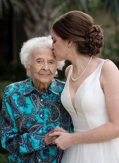 an older woman is kissing the younger woman's cheek