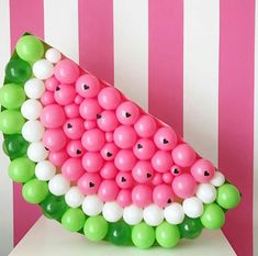 a watermelon shaped balloon sculpture with green, white and pink balloons on it