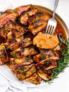 grilled pork chops with rosemary garnish on a white platter, ready to be served