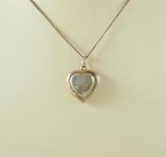 A delightful vintage sterling silver heart shaped double locket for four photographs.  The front engraved with a flower and stylized foliage opening to reveal space for two photographs, no frames or glass. The plain reverse opening to the side to reveal space for two photographs, also no frames or glass. Marked within "925" for sterling silver only. The chain is for display only. Probably Germany 1970s. 6.2g The small photographs 1cm x 1cm.  In inches 2/8". The larger photographs 1.5cm x 1.5cm.  In inches 1/2". The locket 2.1cm x 2cm.  In inches 3/4". With bail 2.9cm.  In inches 1 1/8". IN GOOD VINTAGE CONDITION WITH A TINY HOLE TO THE LOWER FRONT: NO FRAMES OR GLASS INTENDED: In good antique condition with a tiny hole to the lower front. Needing another good polish. No frames or glass int Vintage Locket Necklace With Polished Finish For Anniversary, Antique Sterling Silver Locket Necklace For Anniversary, Vintage White Gold Locket Necklace For Anniversary, White Gold Hallmarked Locket Necklace For Wedding, Hallmarked White Gold Locket Necklace For Wedding, Antique Heart Pendant Necklace For Anniversary, Vintage White Gold Jewelry With Heart Charm, Wedding White Gold Hallmarked Locket Necklace, Hallmarked Heart Locket Necklace For Wedding