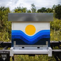 a painted wooden box sitting in the middle of some grass