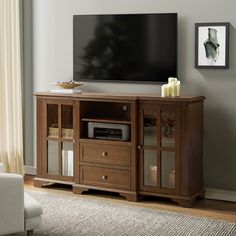 a flat screen tv sitting on top of a wooden entertainment center next to a window