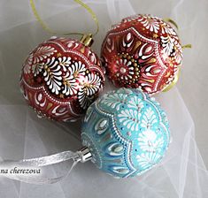 three ornaments are sitting on a white sheet and one is red, the other blue