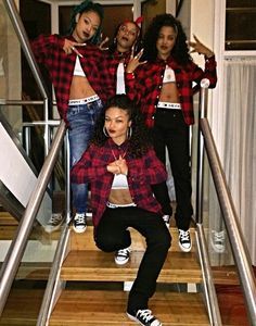 four girls in plaid shirts and black pants posing on stairs with their arms around each other