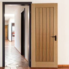 an open door leading to a hallway with tile flooring and wood paneled doors