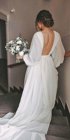 a woman in a white dress is walking down the stairs with her back to the camera