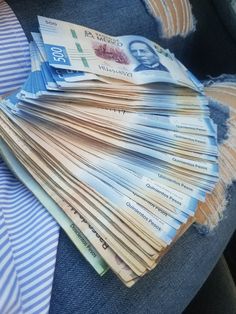 a pile of money sitting on top of a blue chair next to a striped shirt