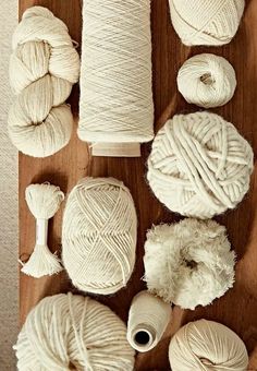 several balls of white yarn are laid out on a wooden surface next to each other