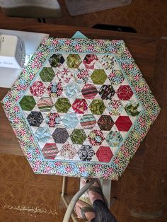 a person standing next to a table with a quilted hexagonal design on it