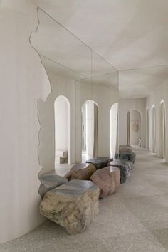 a long hallway with mirrors and rocks on the floor in front of it, all lined up against a wall