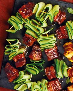 an assortment of meats and vegetables on skewers with sauce drizzled over them