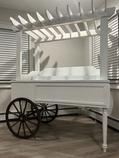 an old wooden cart with wheels in front of shutters and window shades on the wall