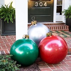 three christmas ornaments sitting on the ground in front of a door with a house number