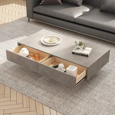 a modern coffee table with open drawers on the bottom, in front of a couch