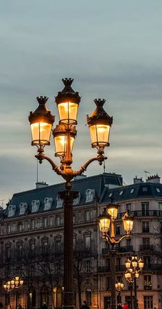 a lamp post in the middle of a street with buildings and lights on it's sides