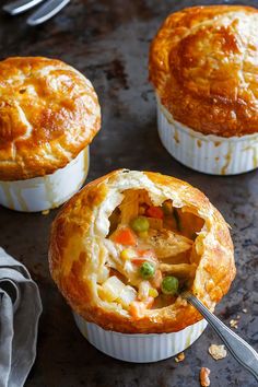 three different types of pies sitting on top of a metal table with forks in them