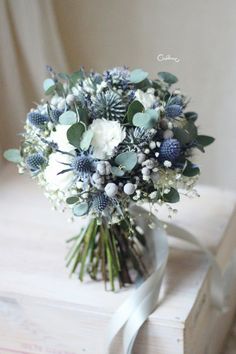 a bouquet of white and blue flowers sitting on top of a wooden box