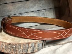 Our beautiful hand-crafted Western stitched English Bridle Vegetable-tanned leather belts that we line with a beautiful tan suede giving this belt durability and strength, yet still making it flexible for comfort. The thickness (13oz.) of this belt is perfect for carrying a gun or other accessories that attach to your belt, or if you prefer to wear for the high end appearance this gives any attire. **COLOR PREFERENCE -Golden Brown -Buck Brown -Rich Brown -Havana **BUCKLE PREFERENCE -Antique Nick Bridle Leather Belts And Suspenders For Everyday Use, Western Belts With Belt Loops For Everyday Use, Fitted Leather Belts And Suspenders, Classic Adjustable Embroidered Belt, Adjustable Embroidered Leather Belt, Leather Western Belts For Everyday, Concealed Carry Belt, Belt Western, Tan Leather Belt