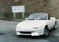 a white sports car driving down the road