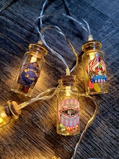 three glass jars with lights attached to them sitting on a wooden table next to some string lights