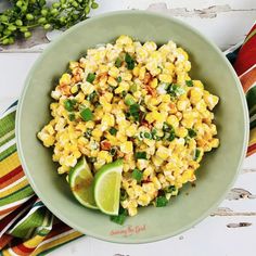 a green bowl filled with corn and garnished with cilantro on top