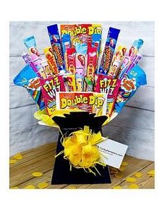 a bouquet of candy and candies in a black vase with yellow bow on top