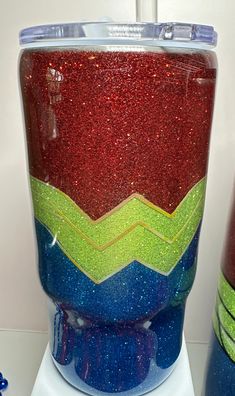 a red and blue tumbler sitting on top of a white counter next to another cup