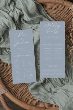 two wedding program cards sitting on top of a wicker basket next to some flowers