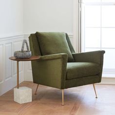 a green chair sitting on top of a hard wood floor next to a white wall