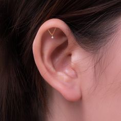 a woman's ear with a single diamond in it