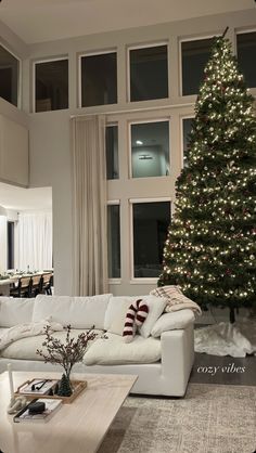 a living room filled with furniture and a large christmas tree in the middle of it