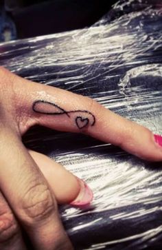 a person's hand with a heart tattoo on it