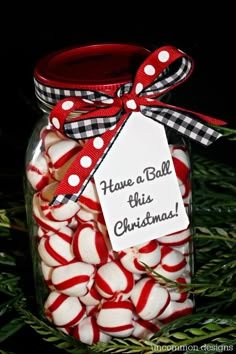 a jar filled with red and white candy canes on top of a green christmas tree