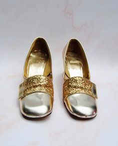 IF ONLY THESE FIT ME These incredible late 1960s golden shoes are an absolute dream shoe! The feature a wide heel, rounded toe and YES, GLITTER These shoes fit a size 6.5 or size 7! Heels are 2.25 inches high. They measure 9.25 inches from toe to heel and about 3 inches across at the balls of the feet. FREE SHIPPING! Good vintage condition - some overall wear and scuffs all over both shoes. The fabric is pulling off a smidge on the inside of the heel. Please see photos. All measurements are appr Gold Court Shoes With 4-inch Heel And Almond Toe, Gold Heels With Padded Heel For Galas, Gold Glitter Heels With Round Toe, Vintage Round Toe Wedding Shoes For Party, Gold Almond Toe Heels For Galas, Gold Closed Toe Court Shoes Medium Width, Gold Wedding Shoes With Padded Heel And Round Toe, Vintage Gold Heels With 4-inch Heel, Retro Gold Heels For Party