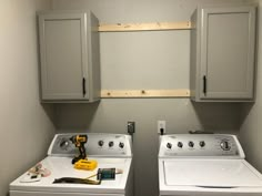 two washers and dryer sitting in a room with cabinets on the wall behind them