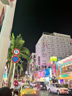 a busy city street at night with cars and people walking on the sidewalk, palm trees in the foreground