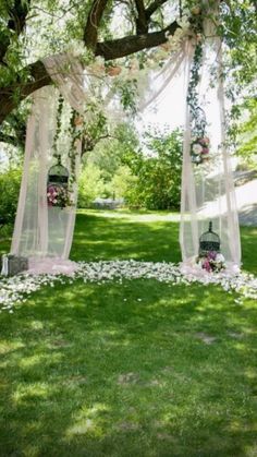 an outdoor ceremony setup with flowers on the ground and white draping over it