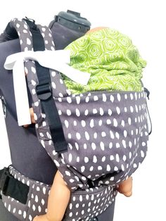 a baby in a carrier with polka dots on it's back and green fabric