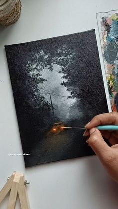 a person holding a pencil in front of a painting