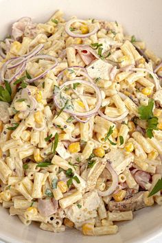 a white bowl filled with pasta salad and garnished with fresh parsley on top